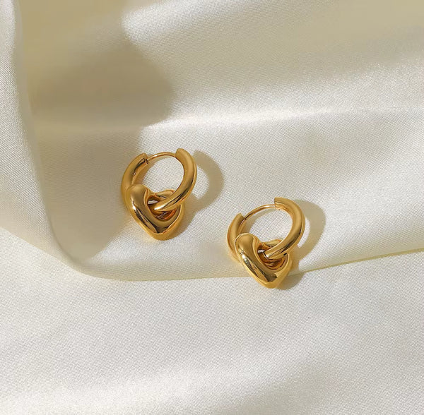 Pair of gold hoop earrings on a light beige fabric background