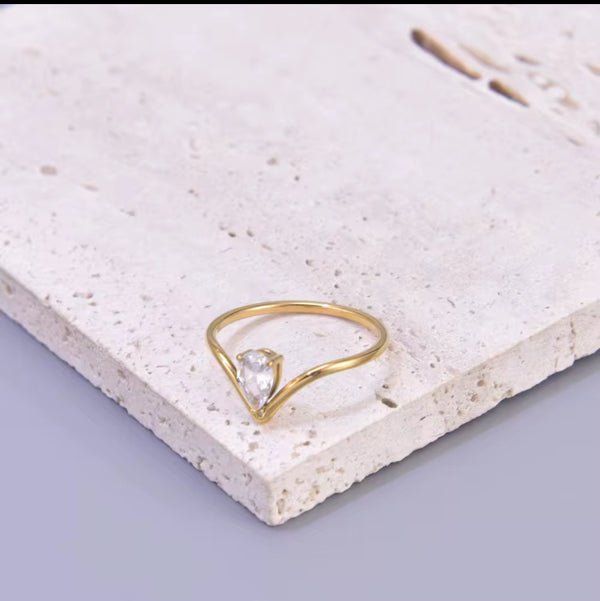 Gold ring with a clear gemstone on a textured white surface